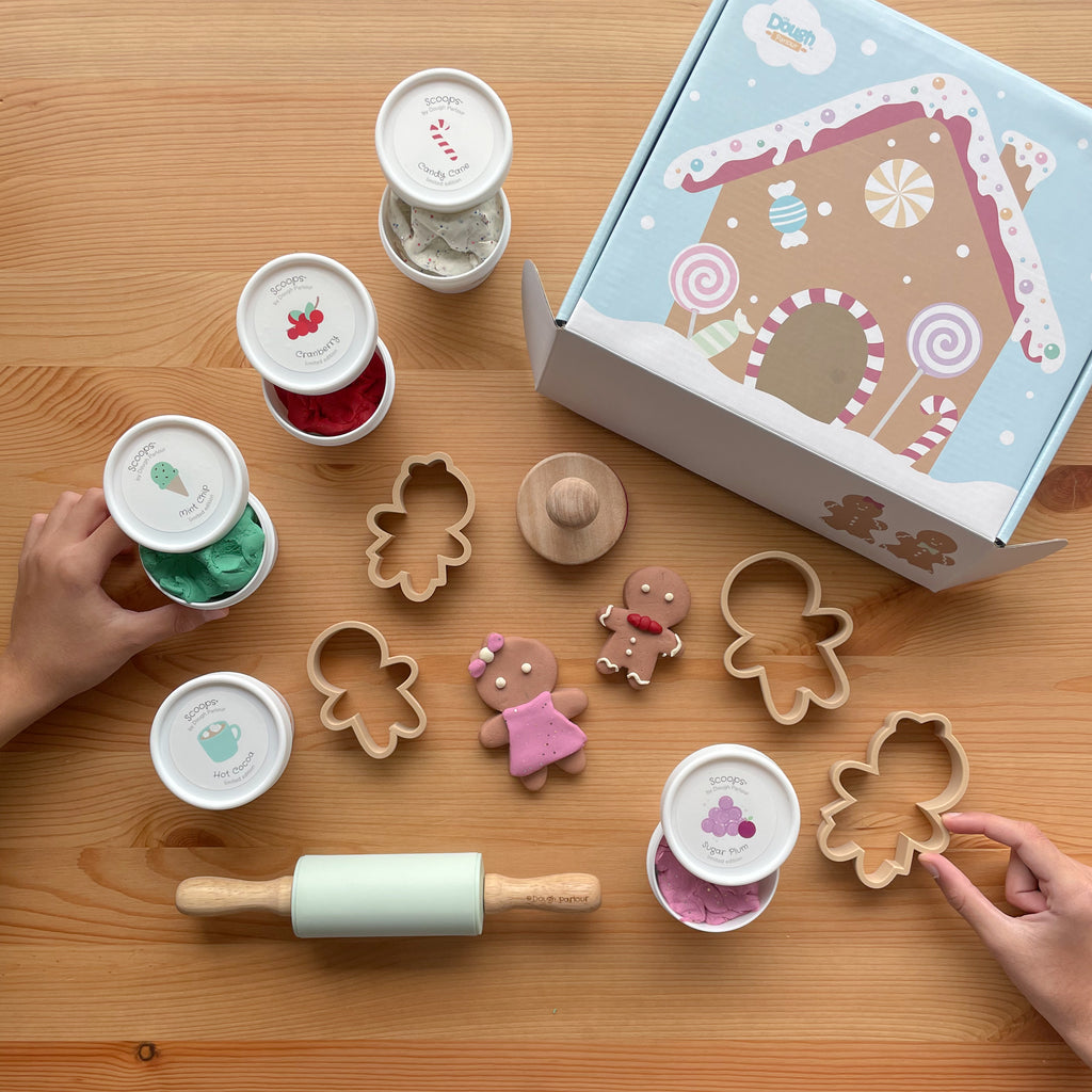 Gingerbread House Playbox closed with kids playing with dough, cutters, rolling pin on a wooden table