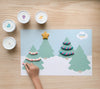 Holiday Playmat showing 4 pine trees decorated with dough by a child on wooden table