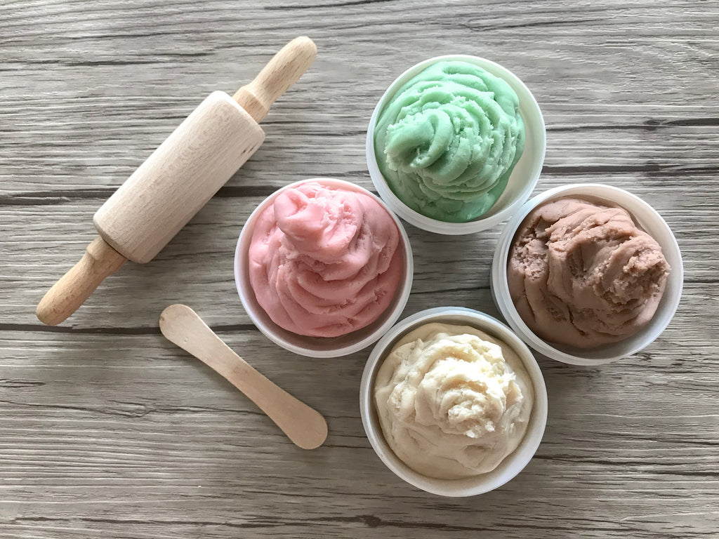 tiny rolling pin with 4 different colored play dough, pink, mint green, brown and white colors of 100% non-toxic dough on wood background