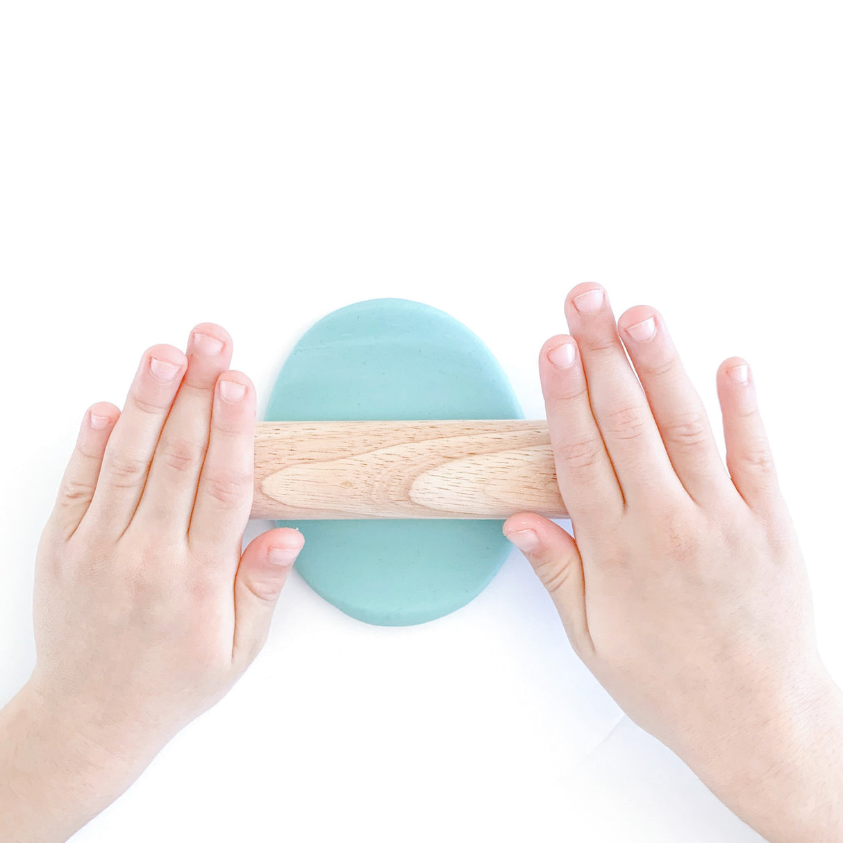 little hands using wooden rolling pin to roll out blue cotton candy scented dough